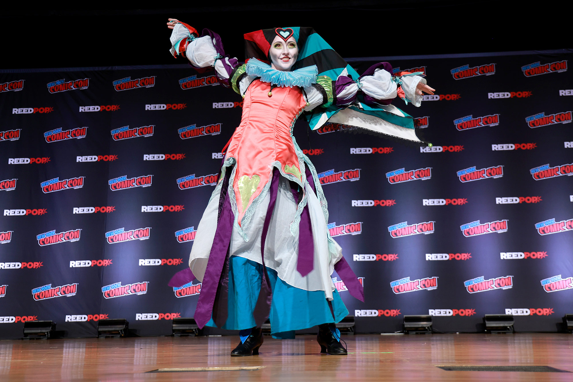 A woman wearing a jester costume on a stage