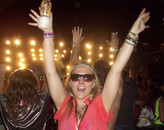girl with sunglasses cheering at a music festival with a water bottle in her hand
