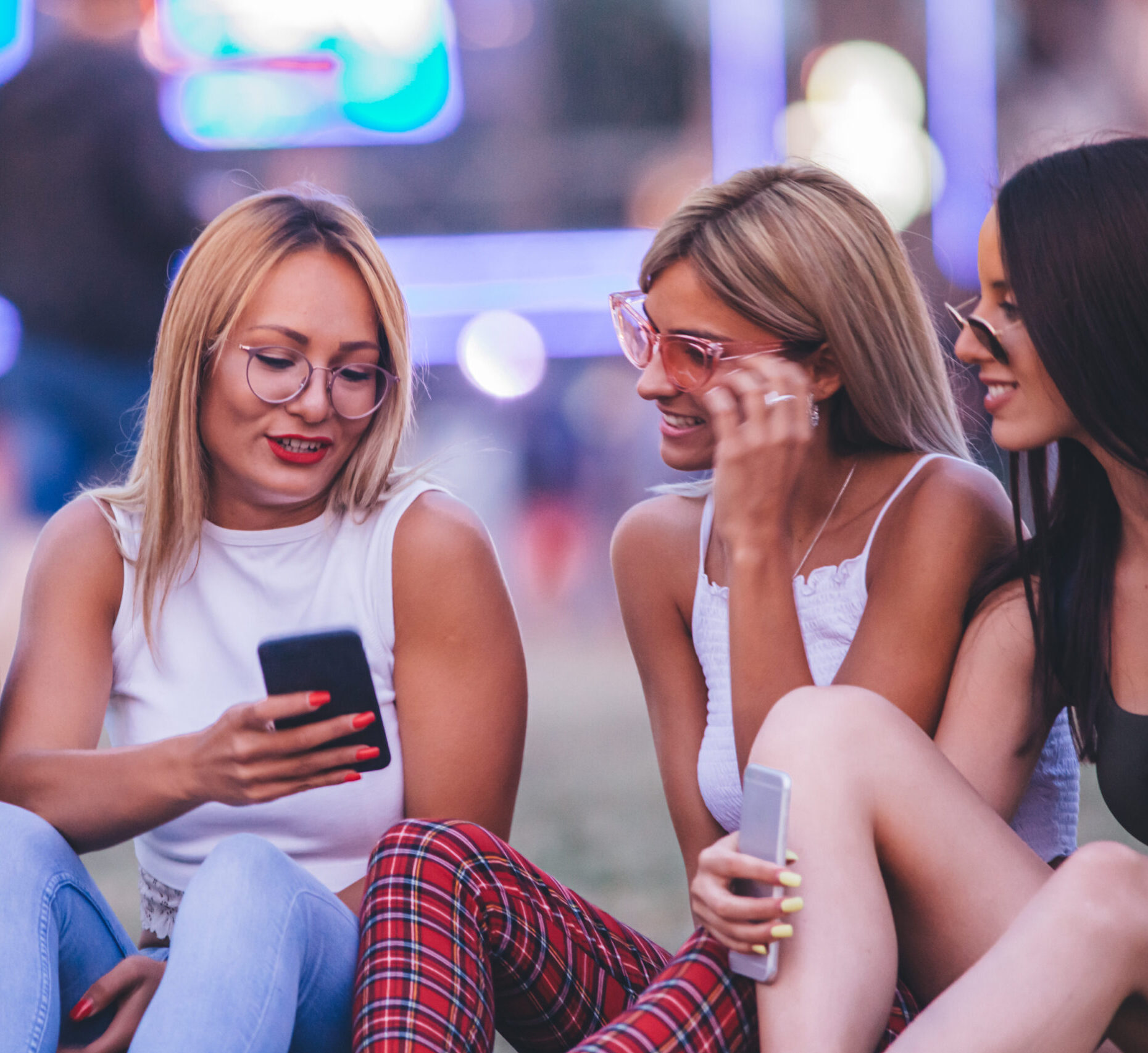 Four friends using their phones at the music festival