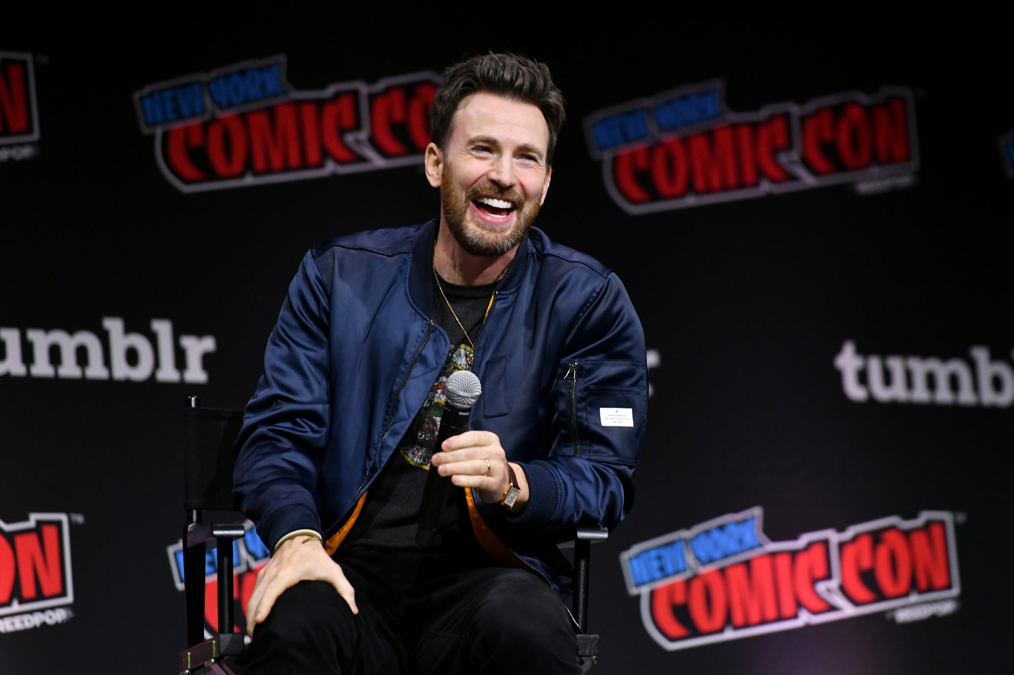 Chris Evans laughing into a microphone at a New York Comic Con panel