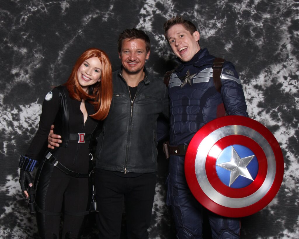 two fans posing with superhero celebrity