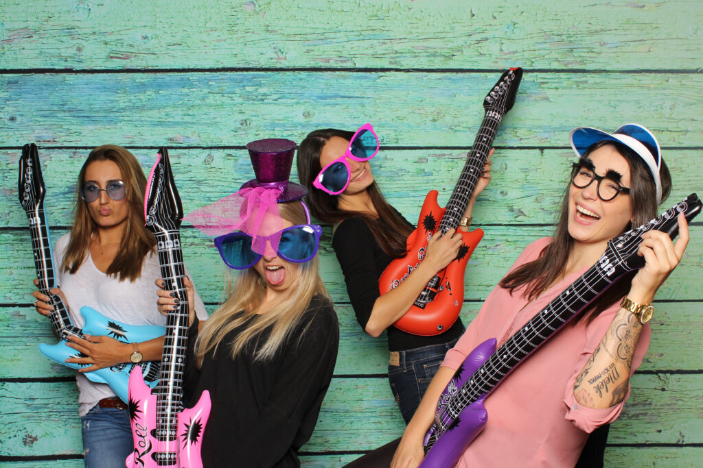 four girls strumming inflatable guitars at a festival photo booth
